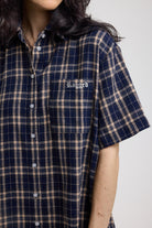 Close up of chest pocket with logo detail on navy and yellow check shirt mini dress