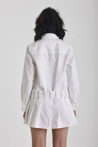 White mini shirt dress with long sleeves, pleated skirt and double eyelet belt, worn by model