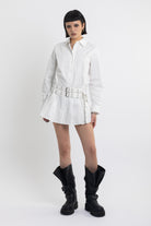 White mini shirt dress with pleated skirt and double eyelet belt, worn by model