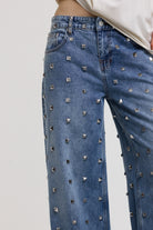 Close up of silver hardware stud detail on blue baggy release jeans, worn by model