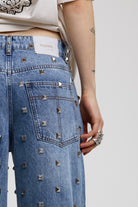 Back image showing leather logo and silver stud detail on blue baggy release jeans, worn by model 