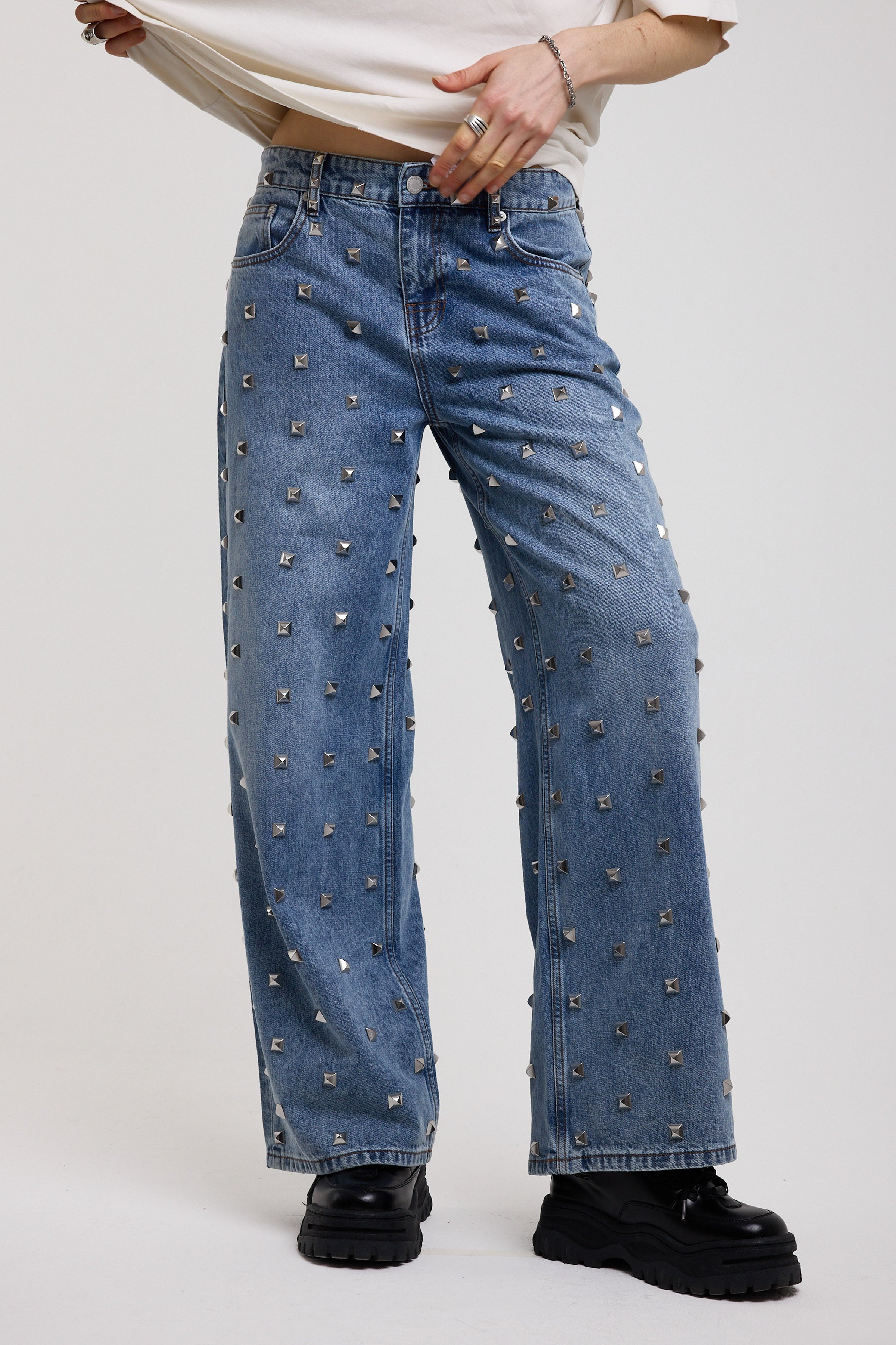 Blue baggy release jeans with silver stud detail, worn by model 