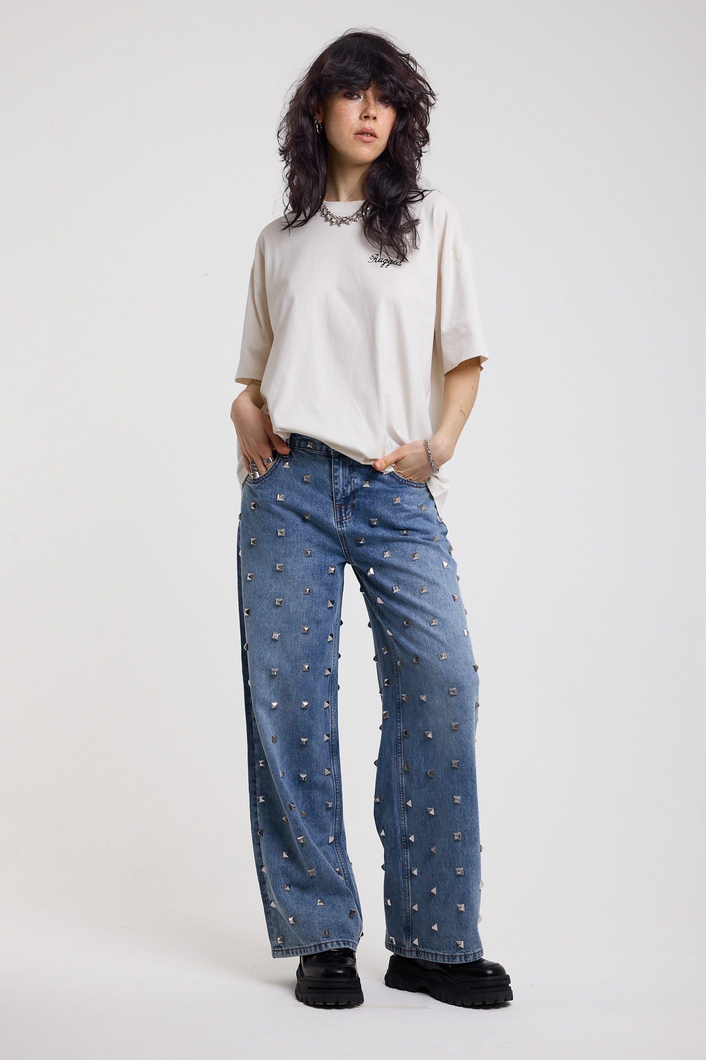 Blue baggy release jeans with silver stud detail, worn by model 