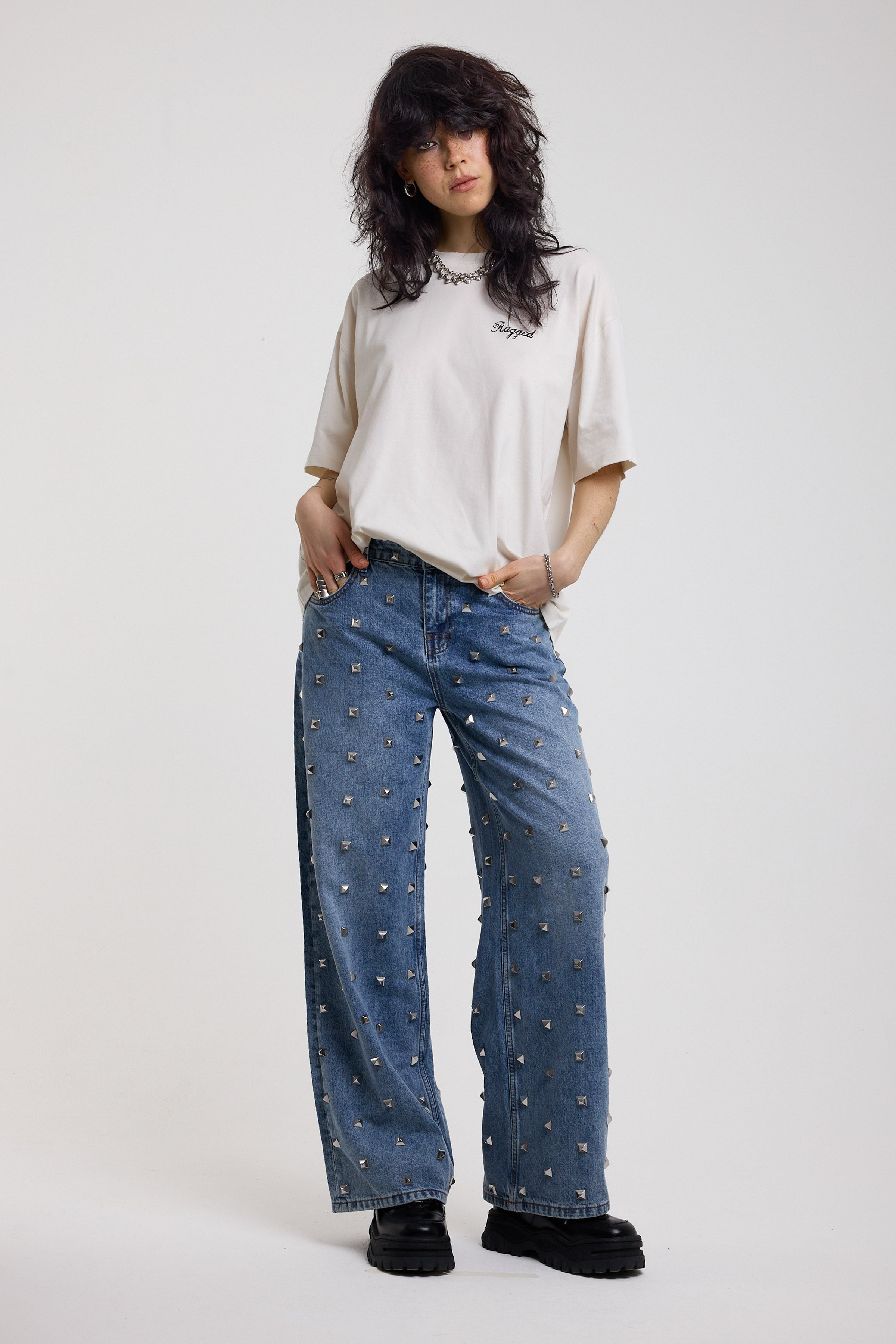 Blue baggy release jeans with silver stud detail, worn by model 