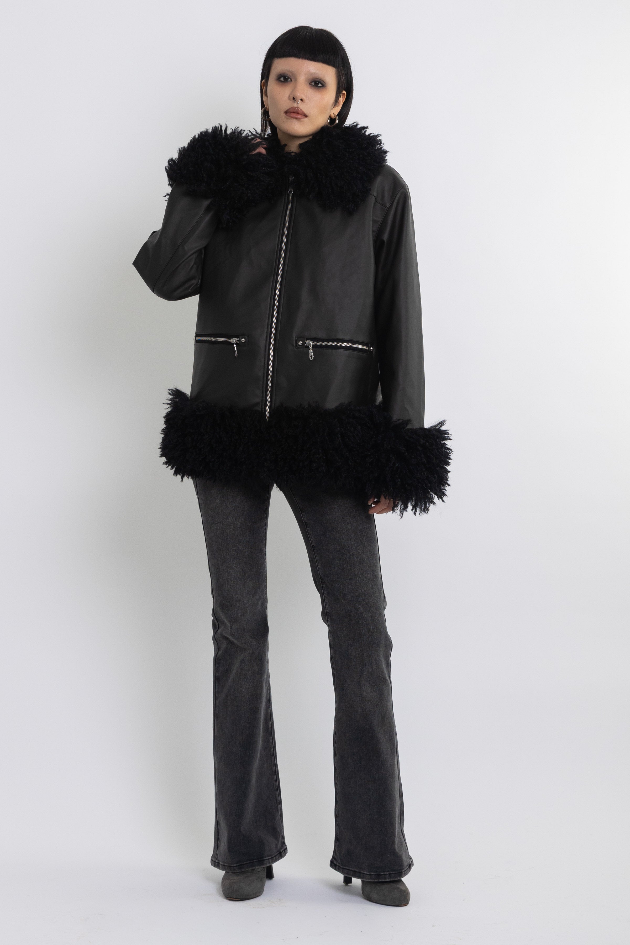 Black faux leather biker jacket with oversized shearling trims and silver hardware, worn by model