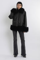 Black faux leather biker jacket with oversized shearling trims and silver hardware, worn by model