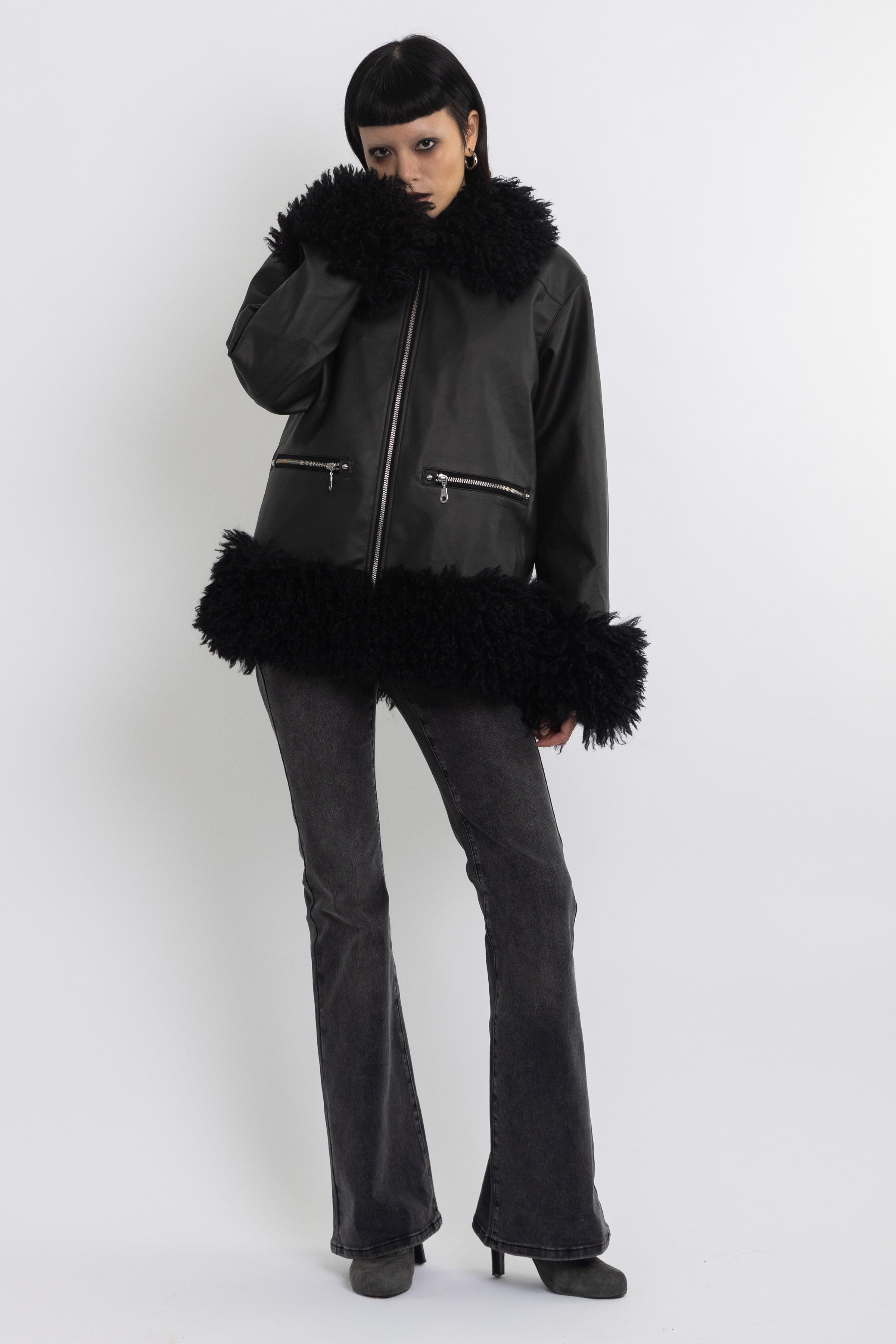 Black faux leather biker jacket with oversized shearling trims and silver hardware, worn by model