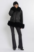 Black faux leather biker jacket with oversized shearling trims and silver hardware, worn by model