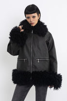 Black faux leather biker jacket with oversized shearling trims and silver hardware, worn by model