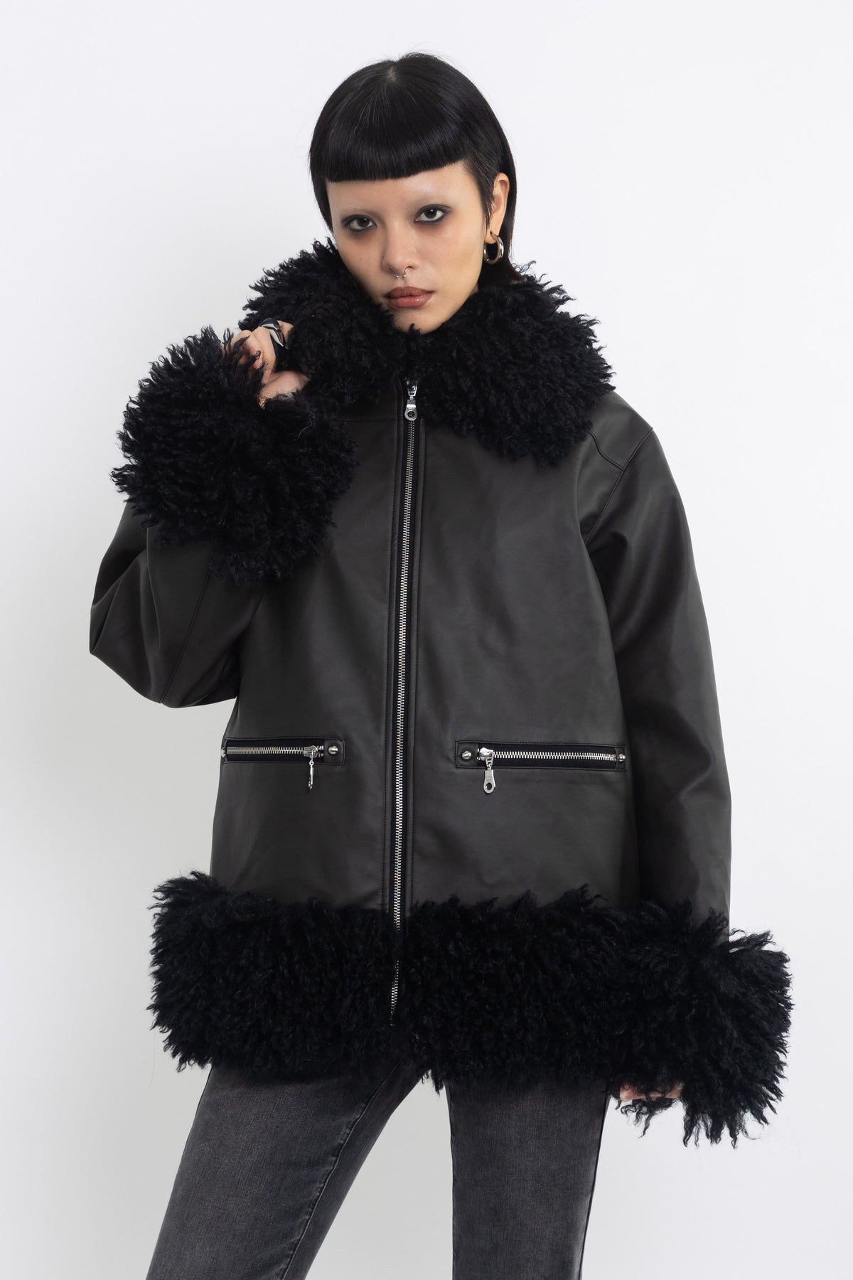 Black faux leather biker jacket with oversized shearling trims and silver hardware, worn by model
