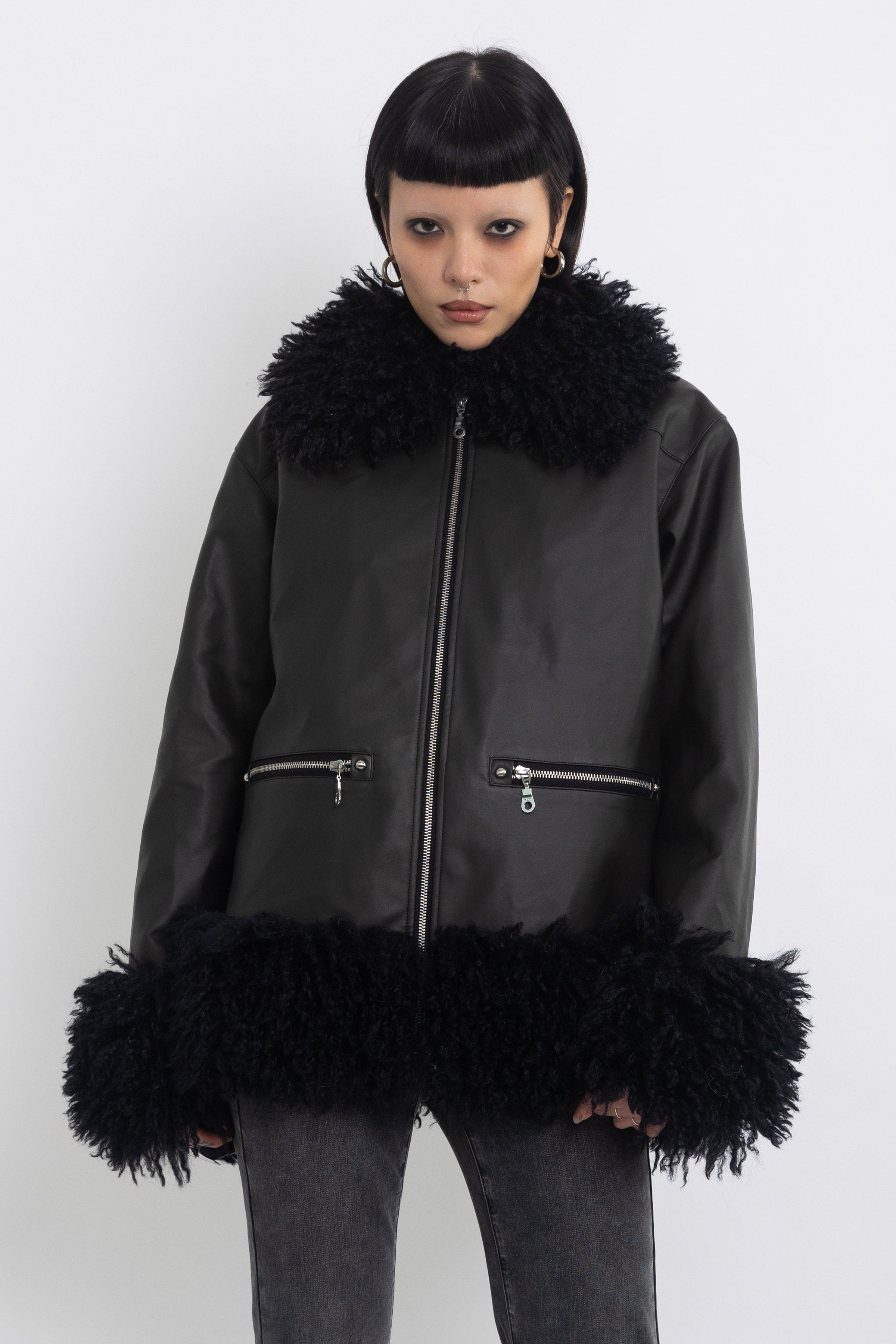 Black faux leather biker jacket with oversized shearling trims and silver hardware, worn by model