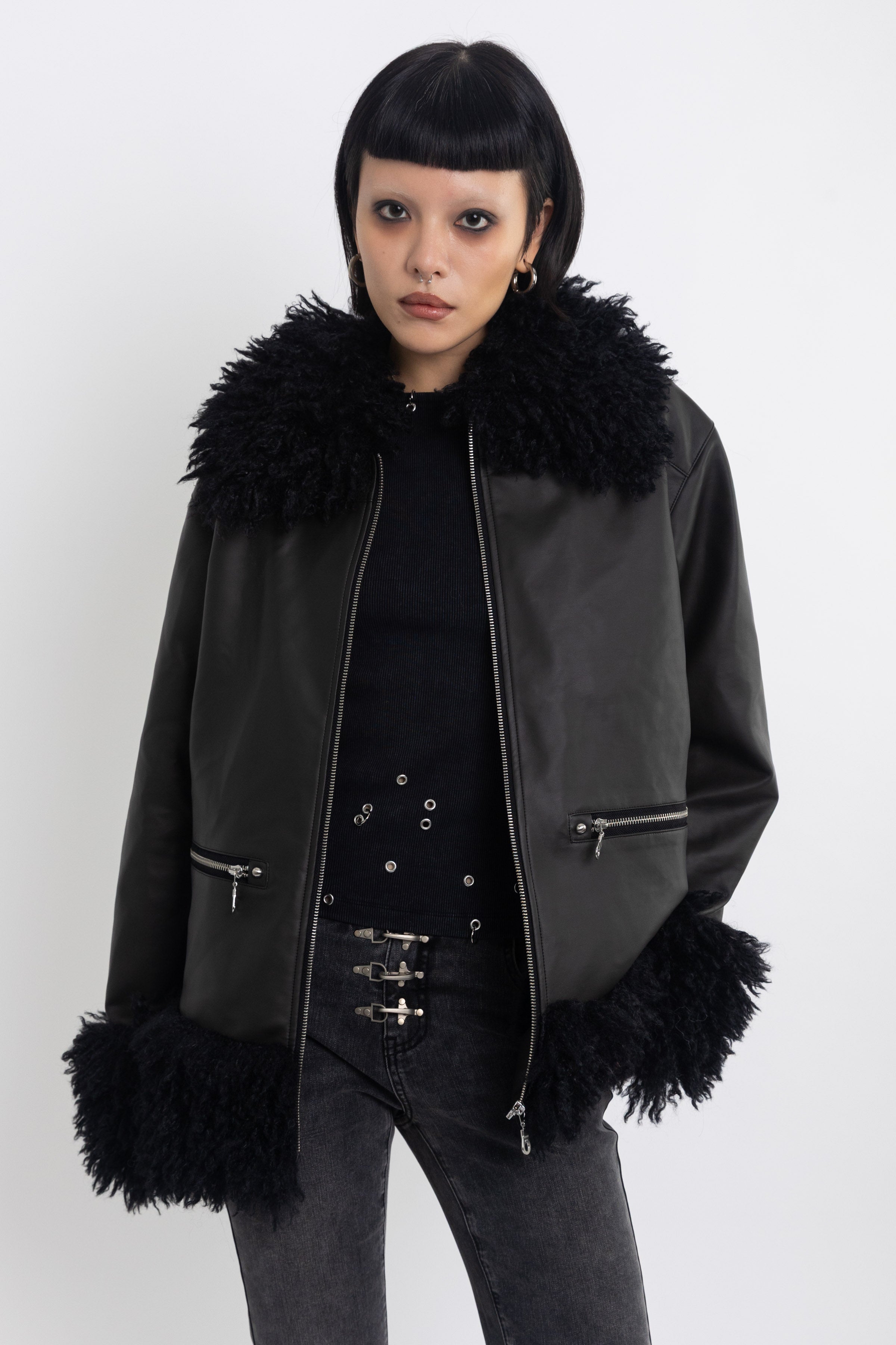 Black faux leather biker jacket with oversized shearling trims and silver hardware, worn by model