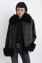 Black faux leather biker jacket with oversized shearling trims and silver hardware, worn by model