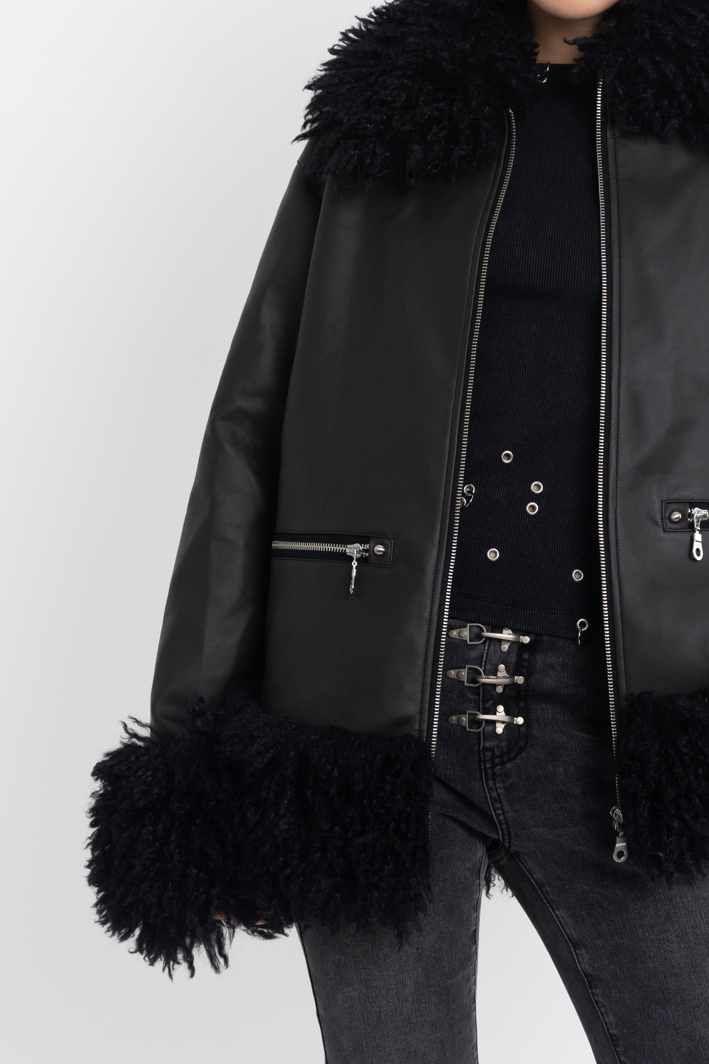 Black faux leather biker jacket with oversized shearling trims and silver hardware, worn by model