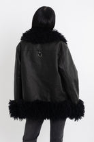 Black faux leather biker jacket with oversized shearling trims and silver hardware, worn by model