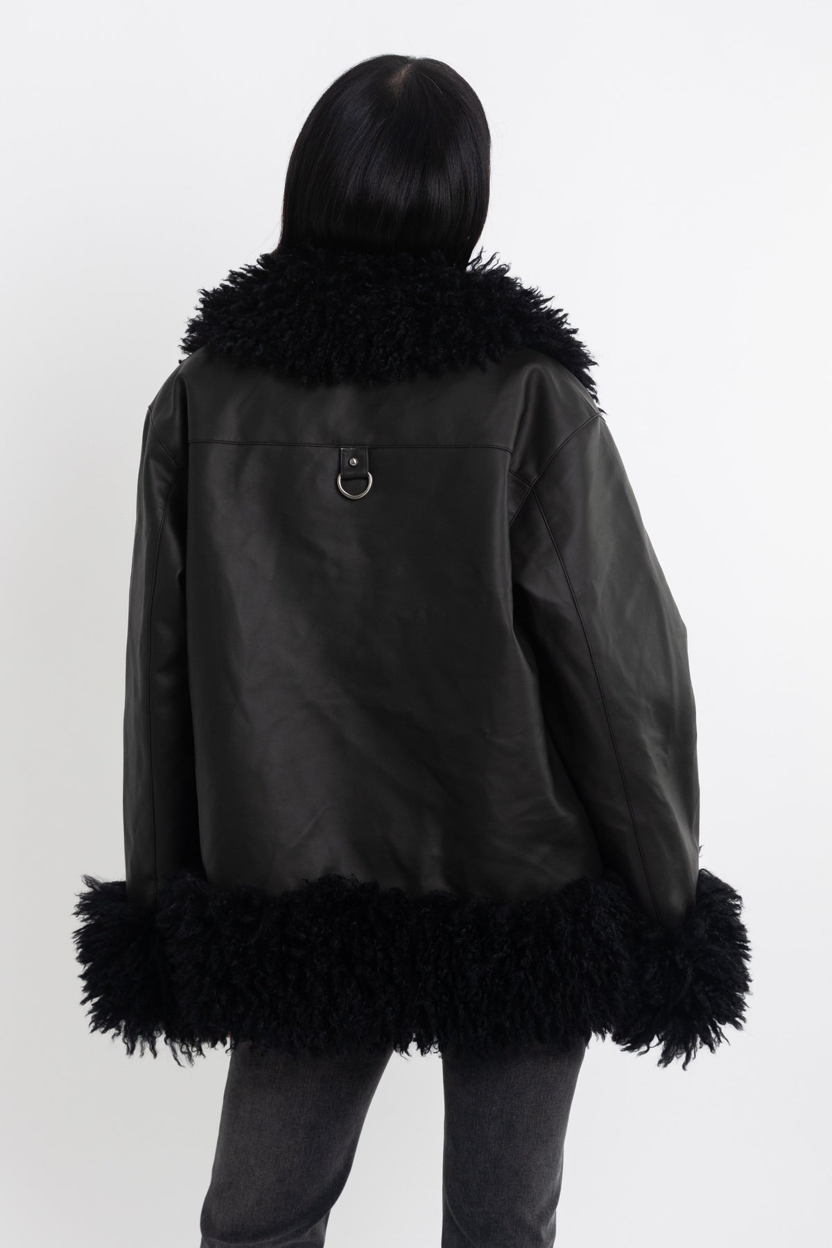 Black faux leather biker jacket with oversized shearling trims and silver hardware, worn by model