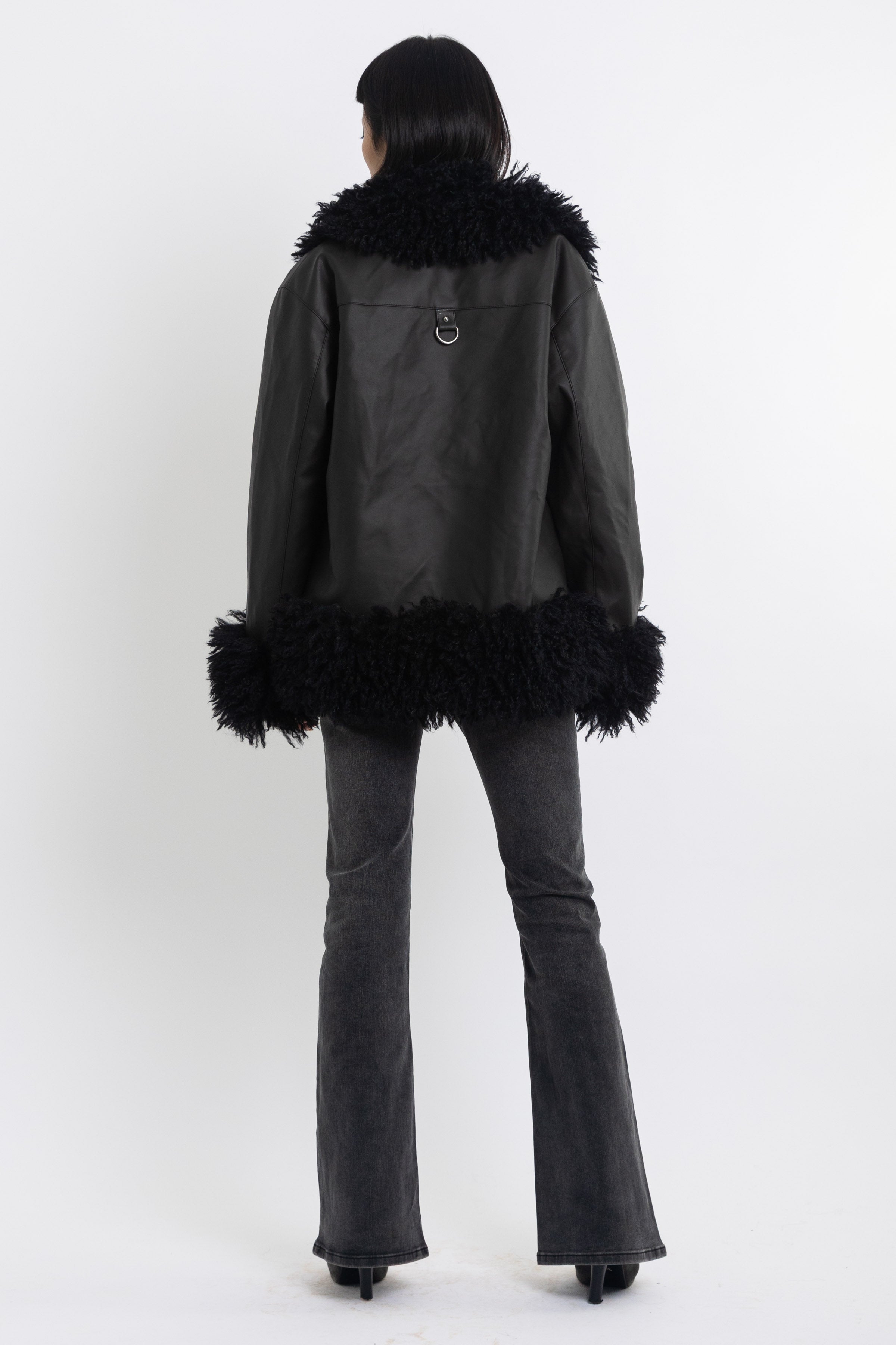 Black faux leather biker jacket with oversized shearling trims and silver hardware, worn by model