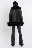 Black faux leather biker jacket with oversized shearling trims and silver hardware, worn by model