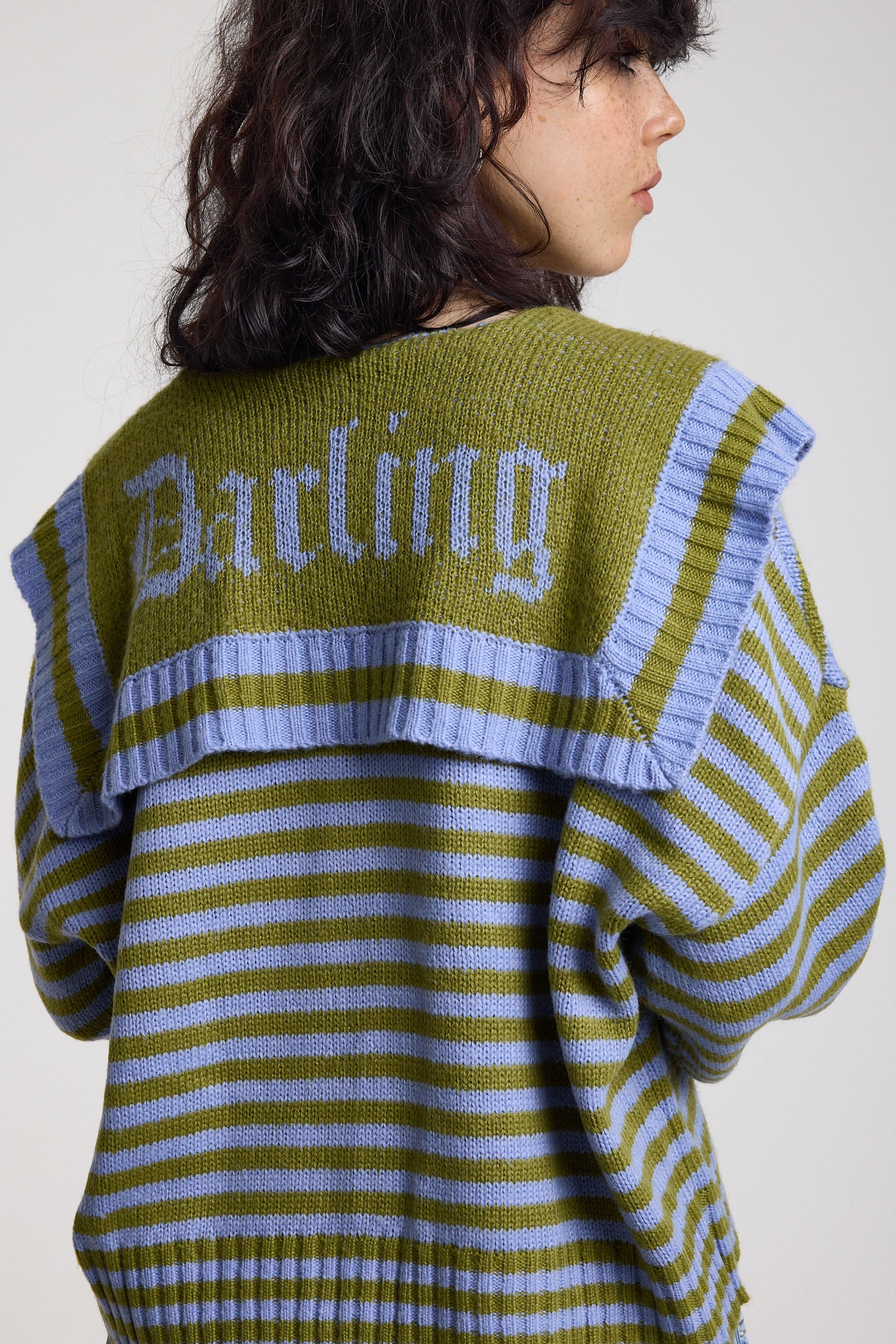 Back image of blue and green stripe knit cardigan with oversized collar featuring a darling motif, worn by a model