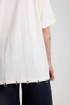 Back of off-white oversized t-shirt showing silver O-ring hardware detail, worn by model