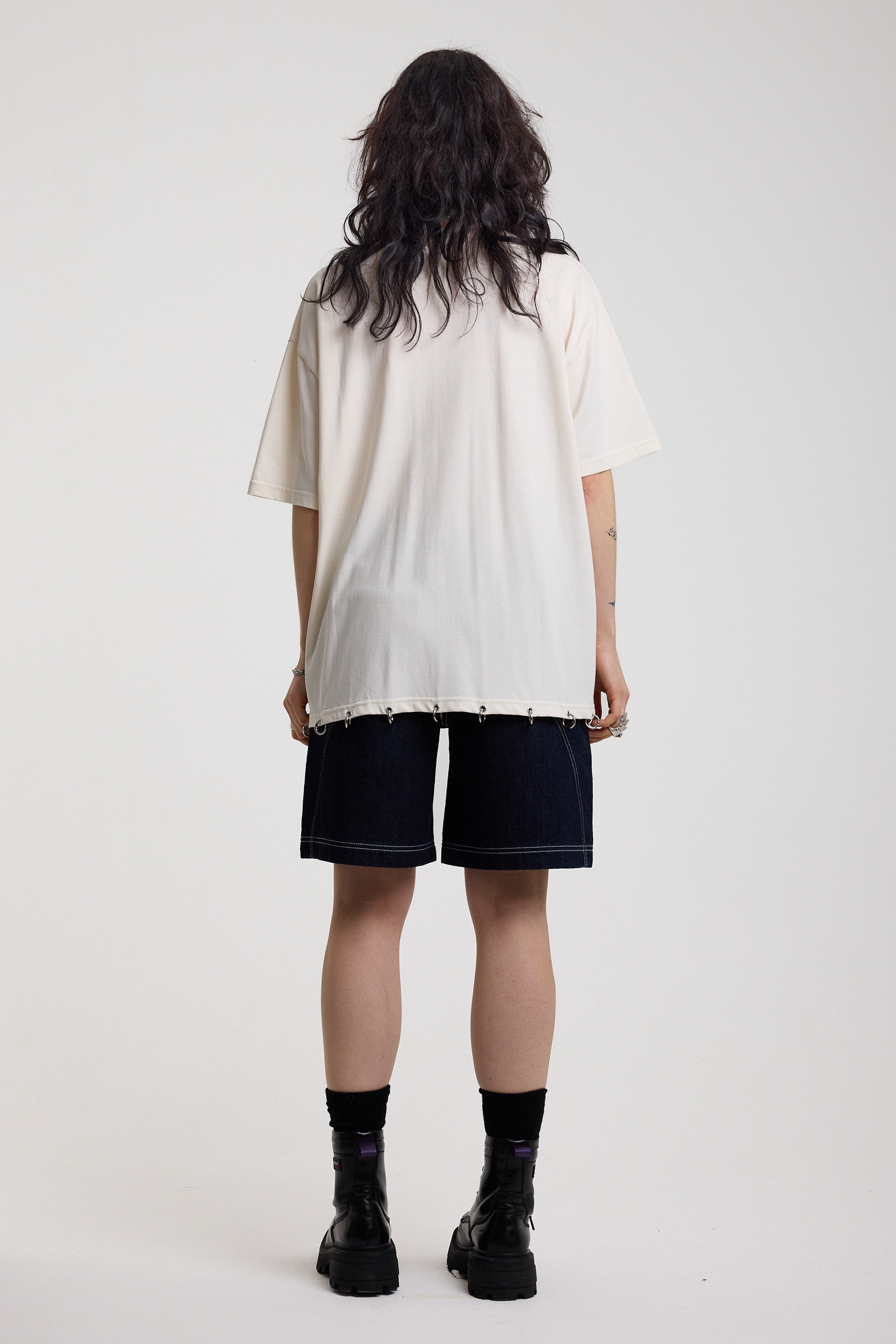 Back of off-white oversized t-shirt showing silver O-ring hardware detail, worn by model