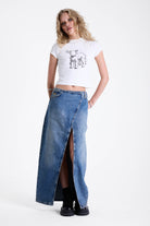 Vintage wash denim maxi skirt with thigh high split and buckle belt fastening, worn by model.