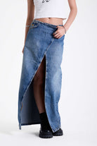 Vintage wash denim maxi skirt with thigh high split and buckle belt fastening, worn by model.