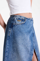 Vintage wash denim maxi skirt with thigh high split and buckle belt fastening, worn by model.