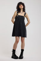 Washed black denim square neck mini dress with eyelet detail straps, worn by model