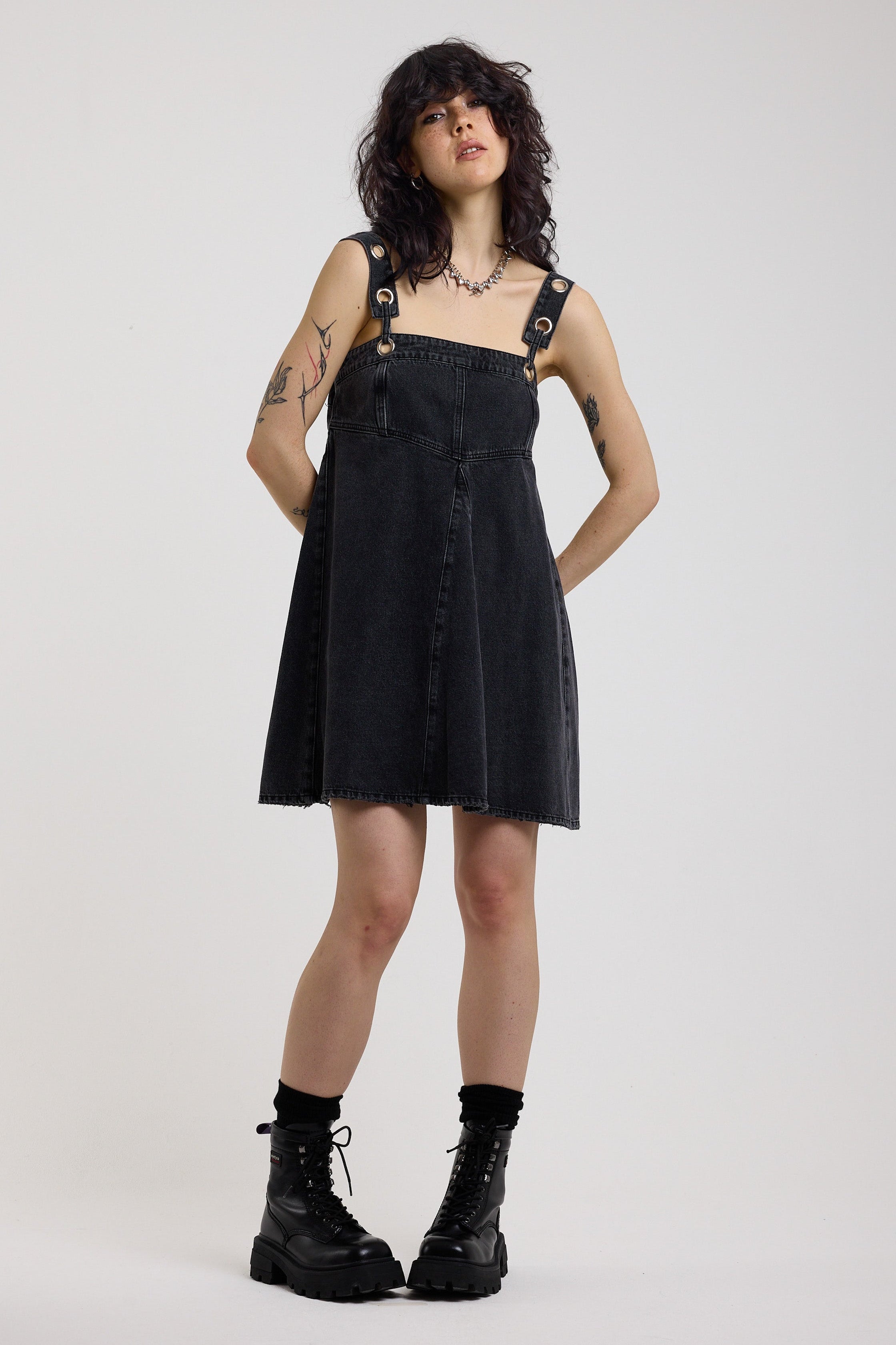 Washed black denim square neck mini dress with eyelet detail straps, worn by model