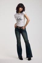 Dark blue flare bootcut jeans with silver D-ring hardware detail, worn by model