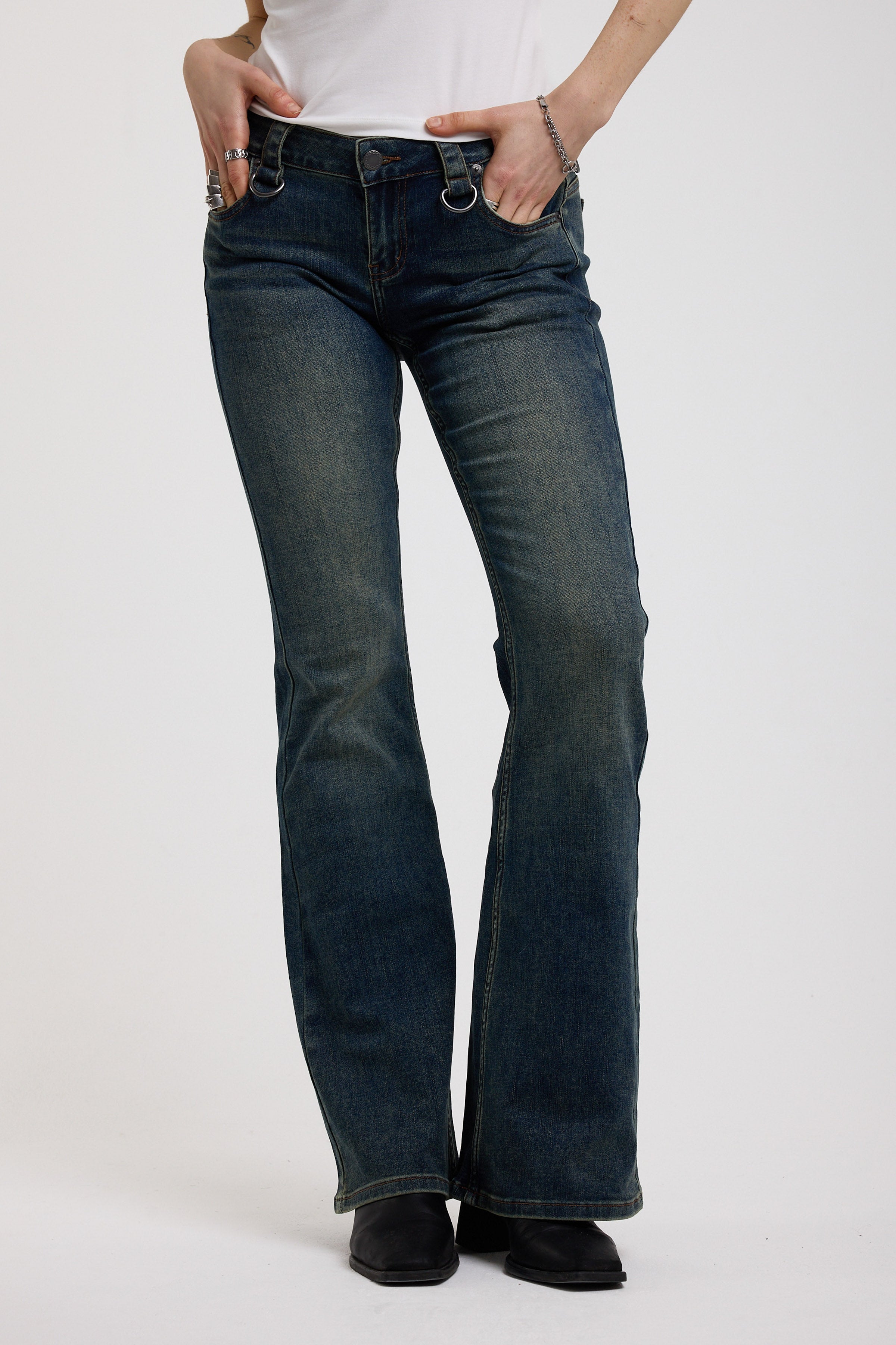Dark blue flare bootcut jeans with silver D-ring hardware detail, worn by model