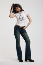 Dark blue flare bootcut jeans with silver D-ring hardware detail, worn by model
