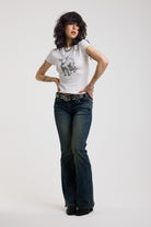 Dark blue flare bootcut jeans with silver D-ring hardware detail, worn by model