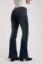 Back of dark blue flare bootcut jeans with silver D-ring hardware detail, worn by model