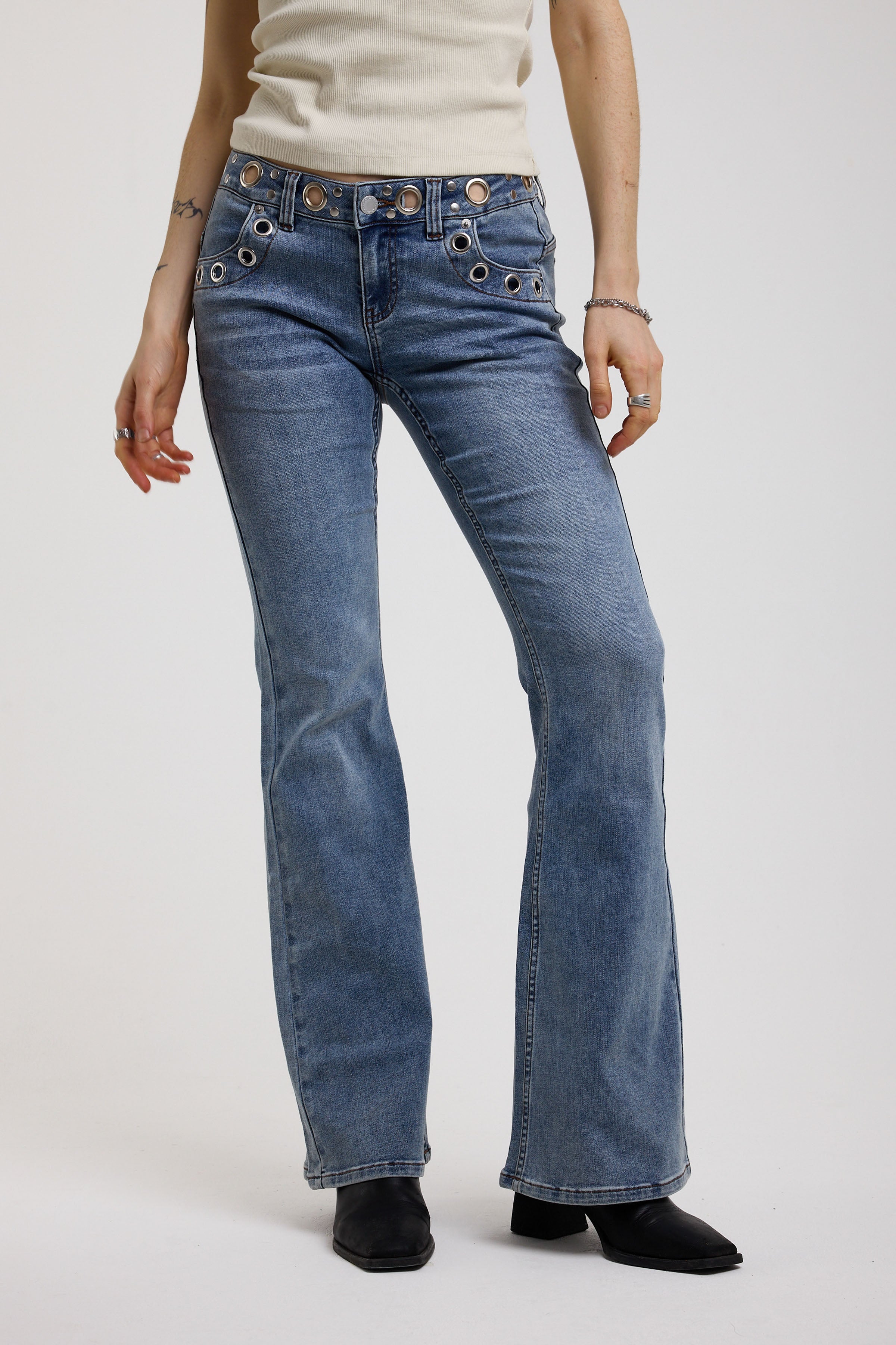 Blue flare bootcut jeans with eyelet and rivet cut out detail, worn by model