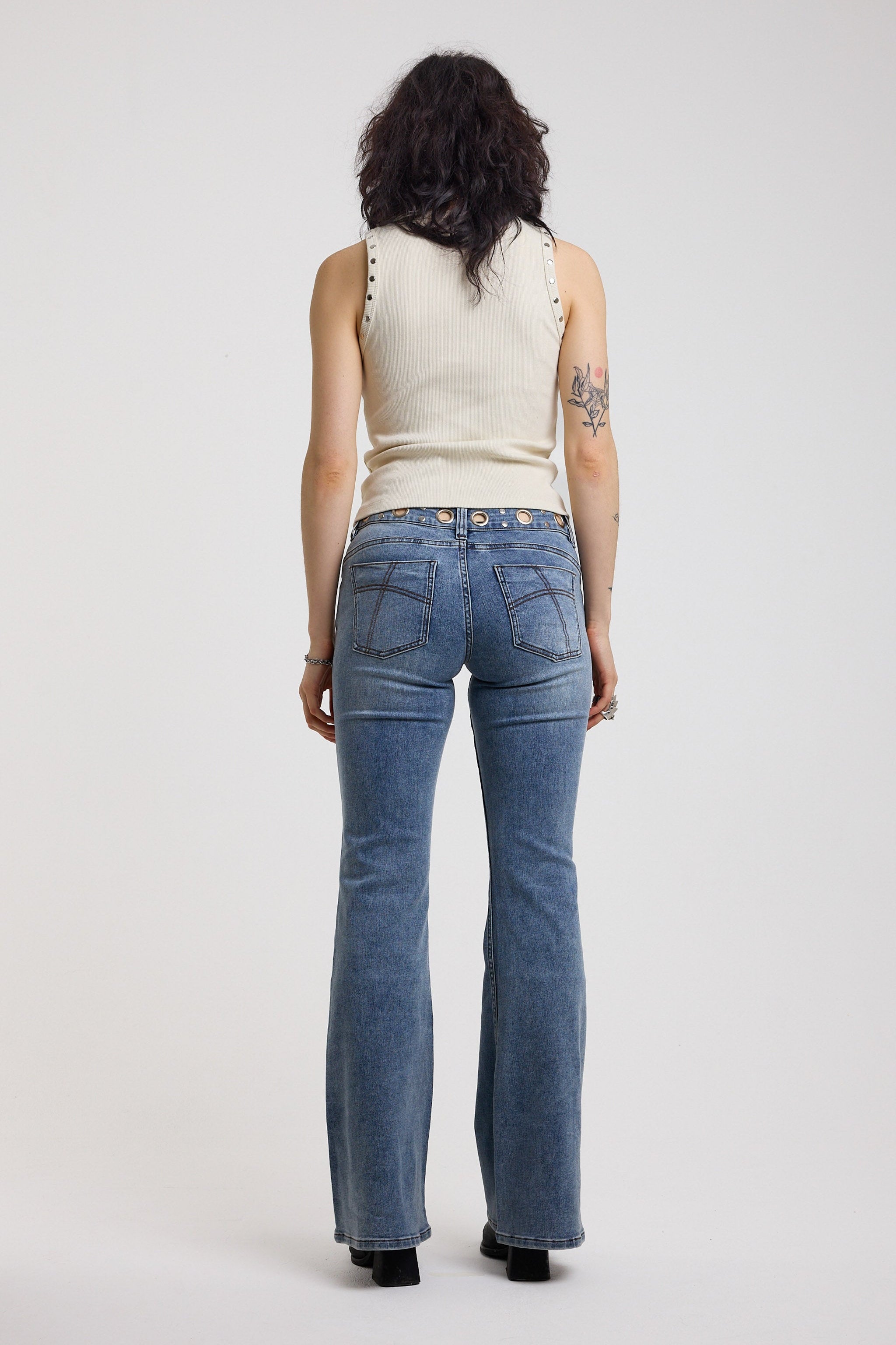 Back image of Blue flare bootcut jeans with eyelet cut out detail, worn by model