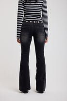 Back image of washed black flare bootcut jeans with eyelet cut out detail, worn by model