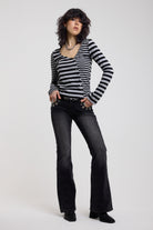 Washed black flare bootcut jeans with eyelet cut out detail, worn by model