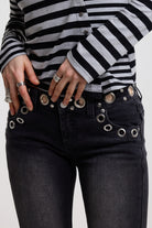 Close up of eyelet cut out detail on washed black jeans, worn by model