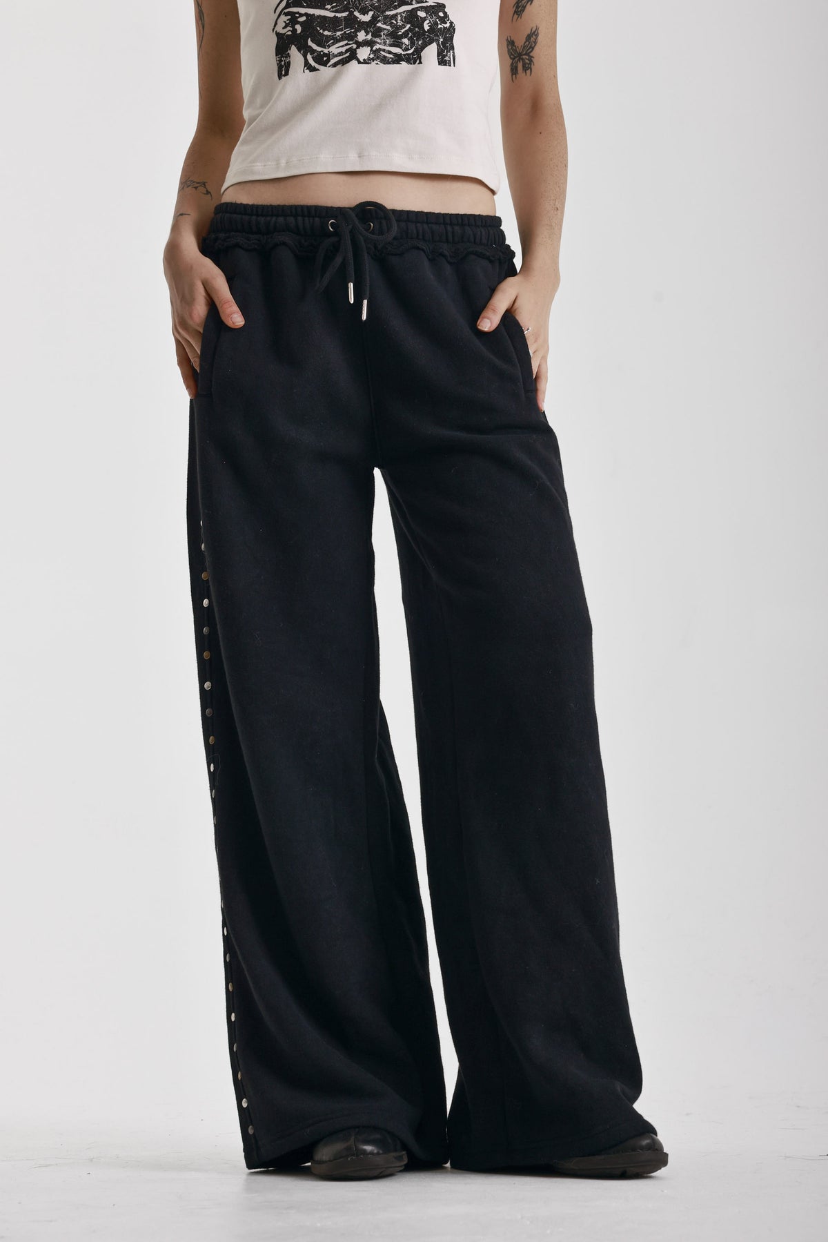 Washed black wide leg sweatpants with mixed metal studs, worn by model