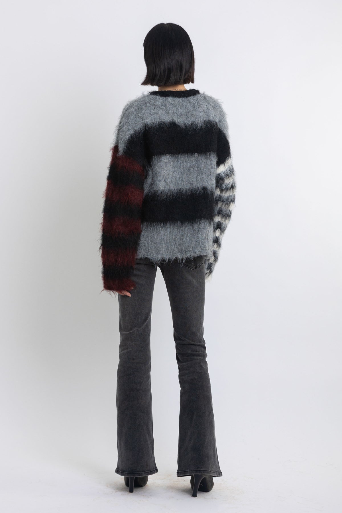Black and grey colourblock stripe fuzzy knit jumper with contrasting stripe sleeves, worn by model