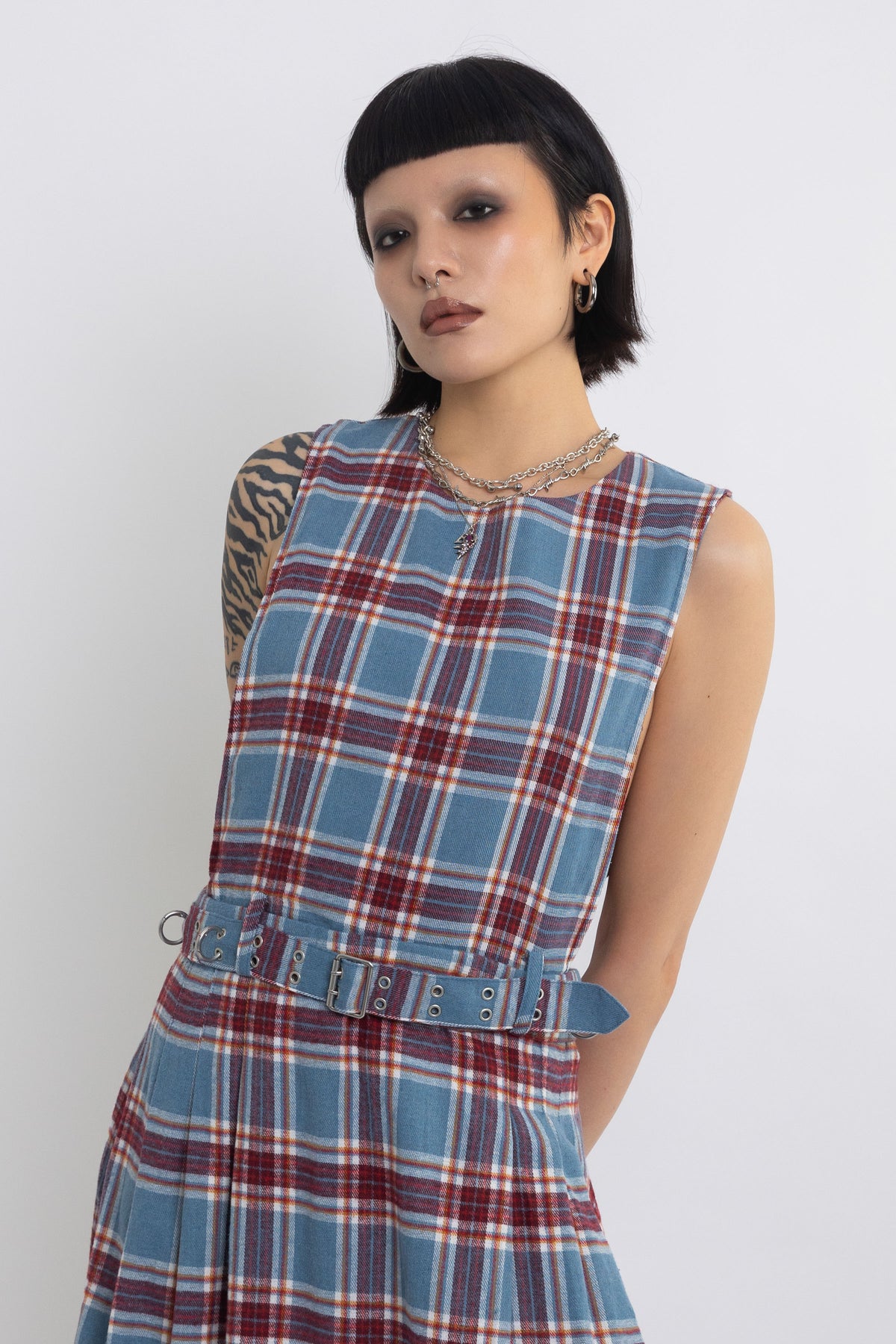 Sleeveless blue plaid check pinafore midi dress with eyelet hardware belt, worn by model