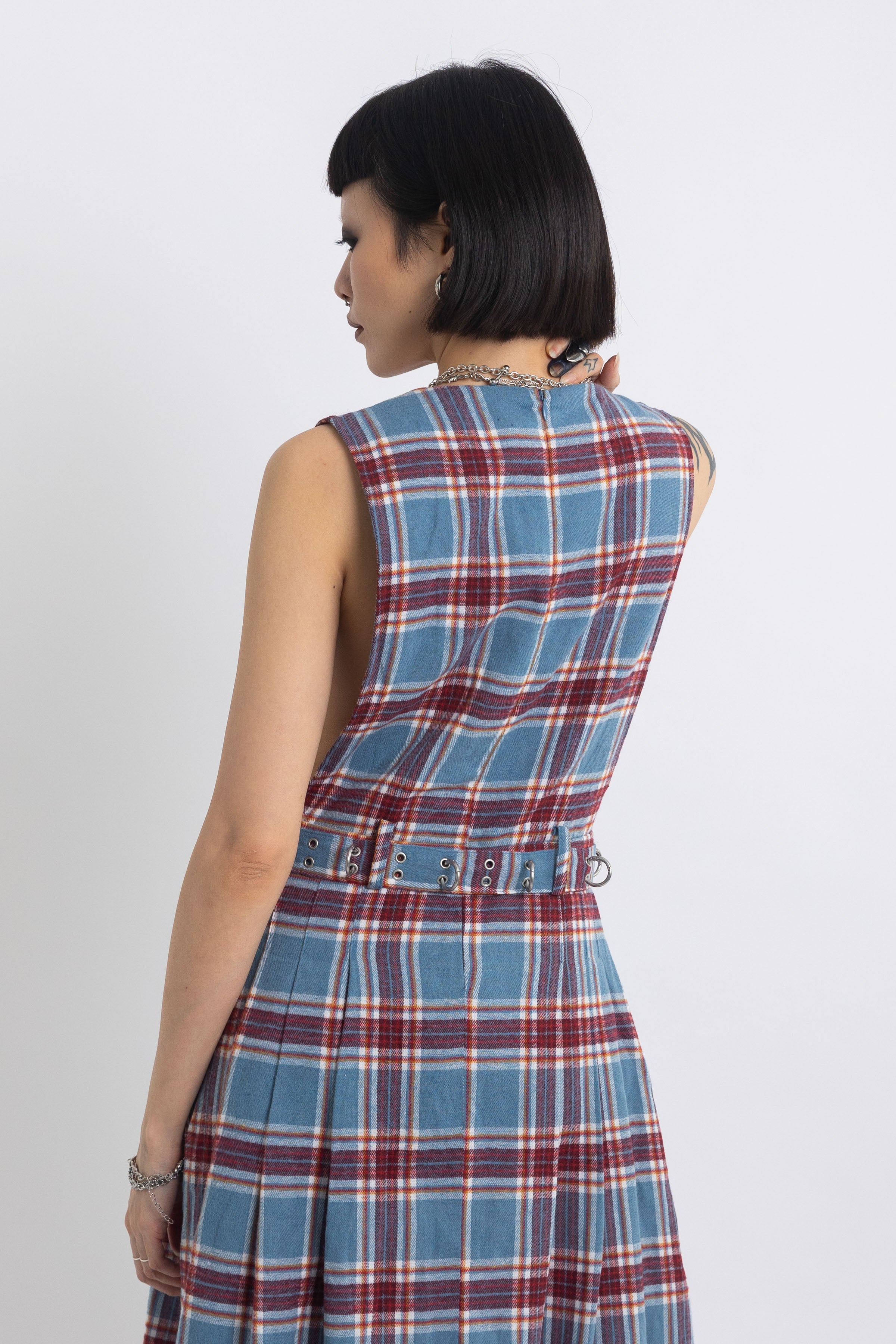 Sleeveless blue plaid check pinafore midi dress with eyelet hardware belt, worn by model