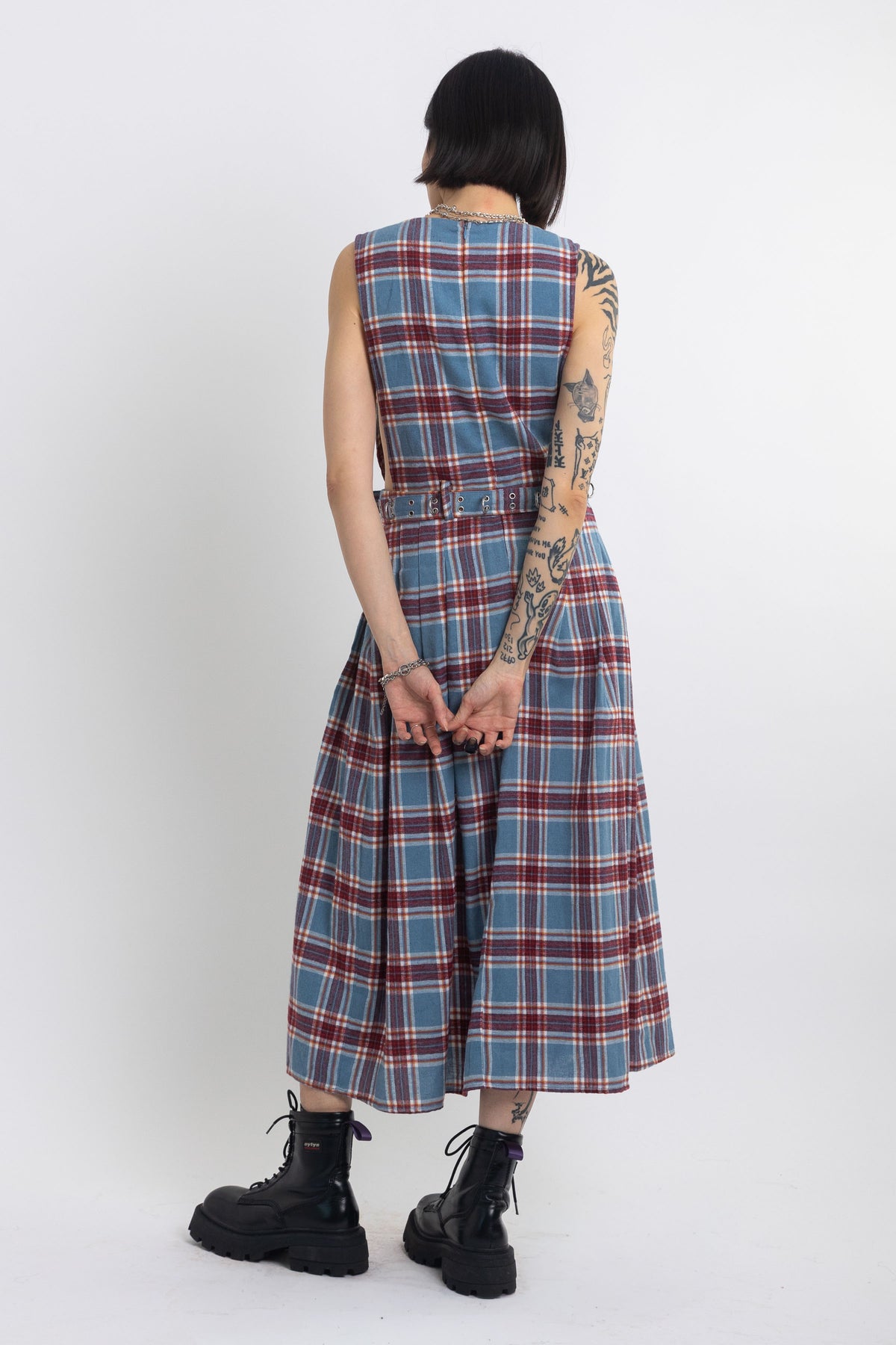 Sleeveless blue plaid check pinafore midi dress with eyelet hardware belt, worn by model
