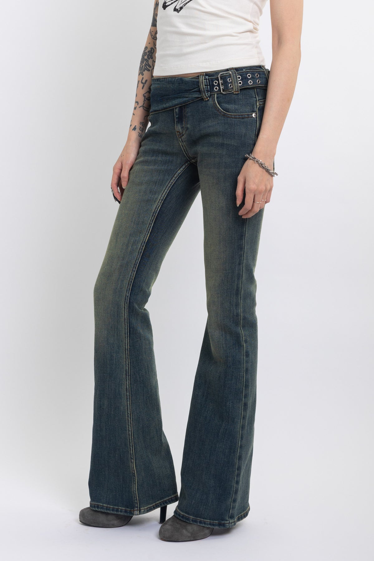 Dirty blue wash belted low rise flare jeans with eyelet detail, worn by model