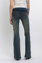 Dirty blue wash belted low rise flare jeans with eyelet detail, worn by model