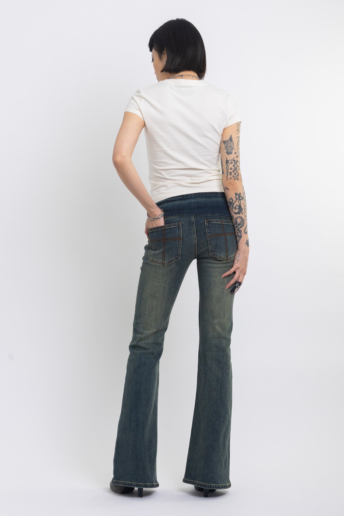 Dirty blue wash belted low rise flare jeans with eyelet detail, worn by model