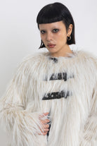 Ecru shaggy faux fur jacket with faux leather eyelet detail straps, worn by model