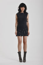 Black ribbed mini dress with slash neck and piercing and stud hardware details, worn by a model